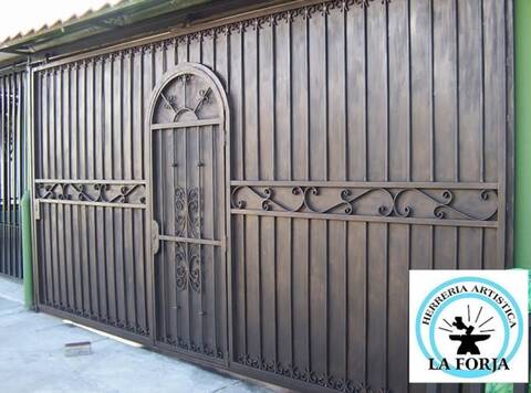 Portón corredizo en hierro forjado con puerta de medio arco al centro